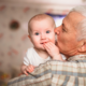 elderly man kissing baby on cheek