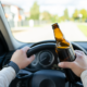 person holding a beer while driving